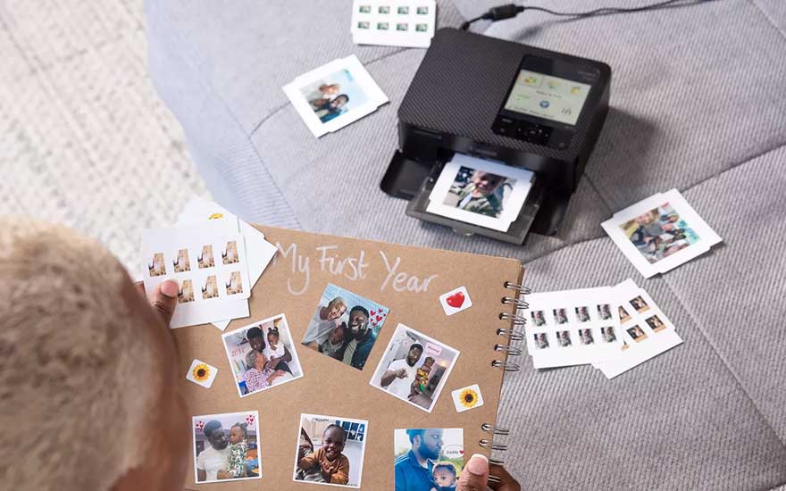Iemand maakt een persoonlijk fotoalbum met familiefoto’s, terwijl een compacte printer nieuwe kleurrijke foto’s op het bed afdrukt.
