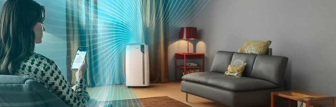 Salon avec canapé gris, lampe sur table rouge et purificateur d'air blanc avec lignes bleues.