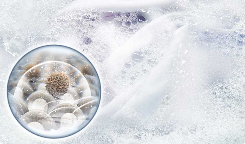 Mousse blanche et bulles partout; à gauche une bulle brillante au cœur granuleux, évoquant un détergent qui se dissout et nettoie.