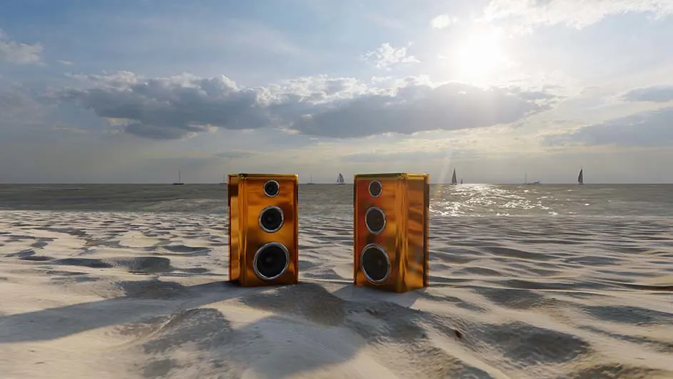Deux haut-parleurs dorés sur une plage de sable, avec une mer calme et un ciel nuageux en arrière-plan.