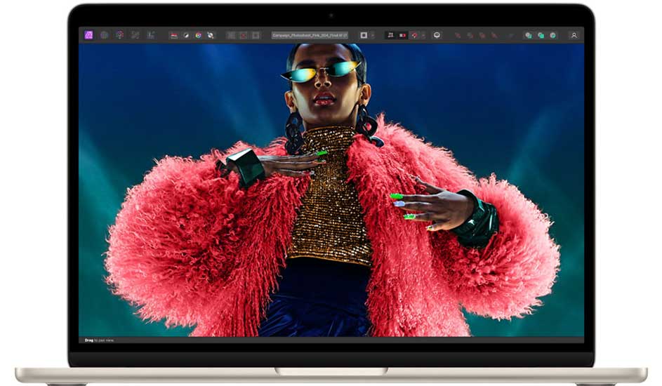 Zilverkleurige laptop met een scherm waarop een persoon met een roze jas en zonnebril te zien is tegen een blauwe achtergrond.