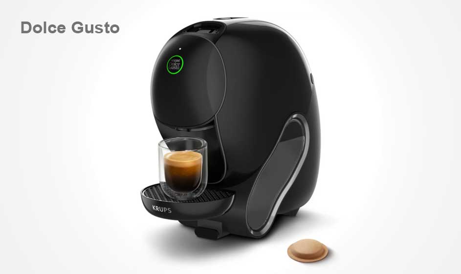 Une machine à café Dolce Gusto noire prépare un petit espresso dans un verre, avec une capsule brune posée sur le fond blanc.