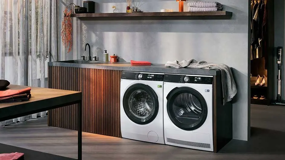 Een wasruimte met een wasmachine en droger naast een houten wastafel onder een plank.