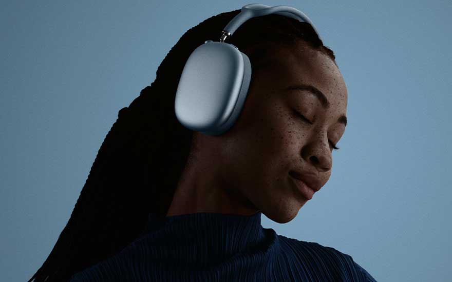 Een persoon met lange gevlochten haren draagt lichtblauwe hoofdtelefoons en sluit rustig de ogen, belicht door een zacht blauwig achtergronlicht.