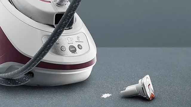 Een stoomstrijkijzer met een slang, een accessoire en wat poeder op een grijze achtergrond.