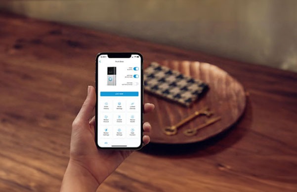 Un smartphone affiche une application sur une table en bois avec un plateau contenant un tissu et des couverts.