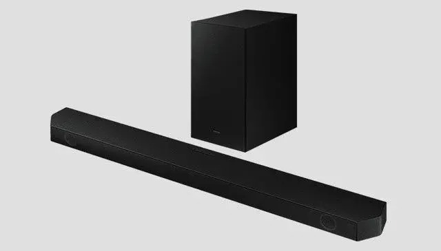 Een zwarte soundbar ligt horizontaal voor een rechtopstaande, zwarte subwoofer tegen een grijze achtergrond.