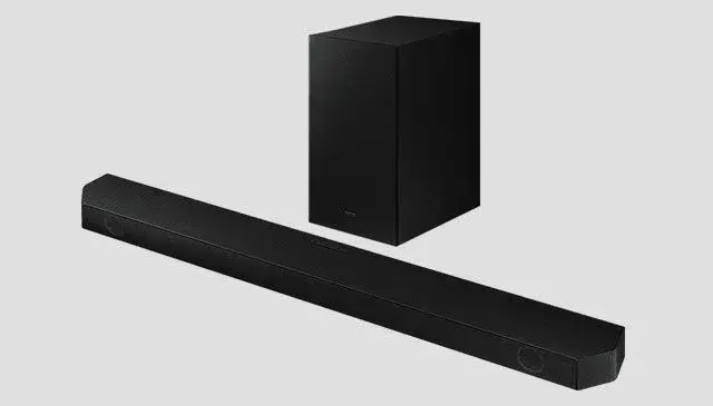 Een zwarte soundbar ligt horizontaal voor een rechtopstaande, zwarte subwoofer tegen een grijze achtergrond.