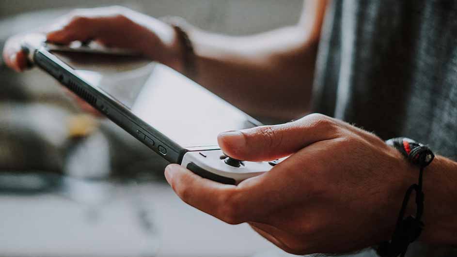 Een persoon houdt een grijze Nintendo Switch-spelcomputer vast met de handen.