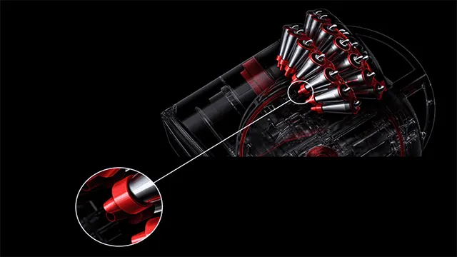 Detail van een rode en zilveren Dyson stofzuiger op een zwarte achtergrond. Een vergroot detail is links onderaan te zien.