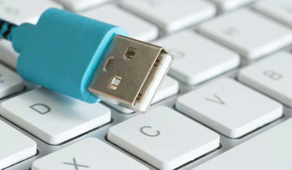 Un câble USB bleu repose sur un clavier blanc. Le connecteur métallique est visible. Clavier avec lettres imprimées.