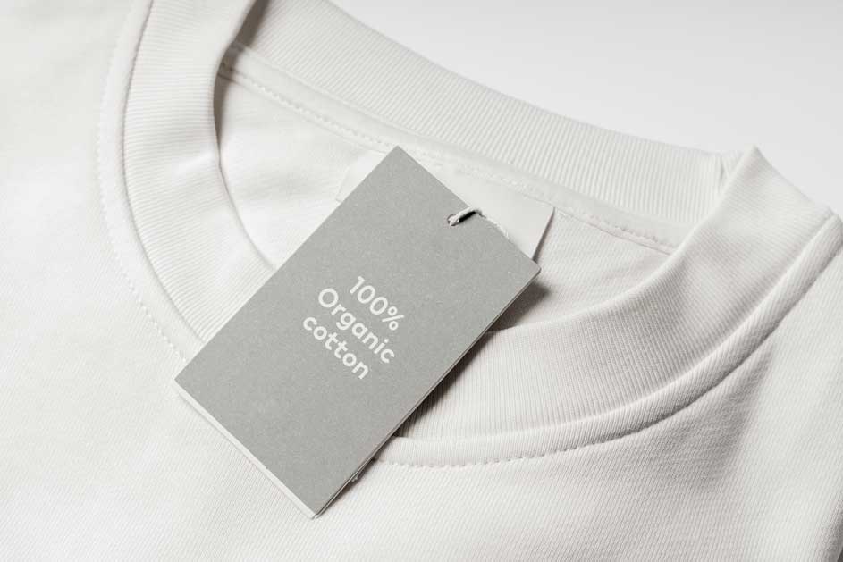 Gros plan d'un t-shirt blanc avec une étiquette grise indiquant "100% coton biologique".