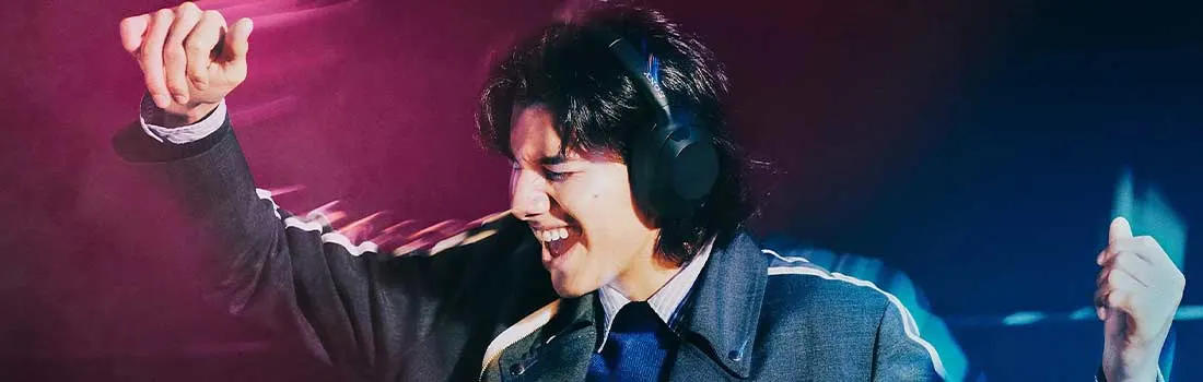 Een jonge man met koptelefoon danst uitbundig in fel gekleurde lichten, volledig opgegaan in de muziek die hij luistert.