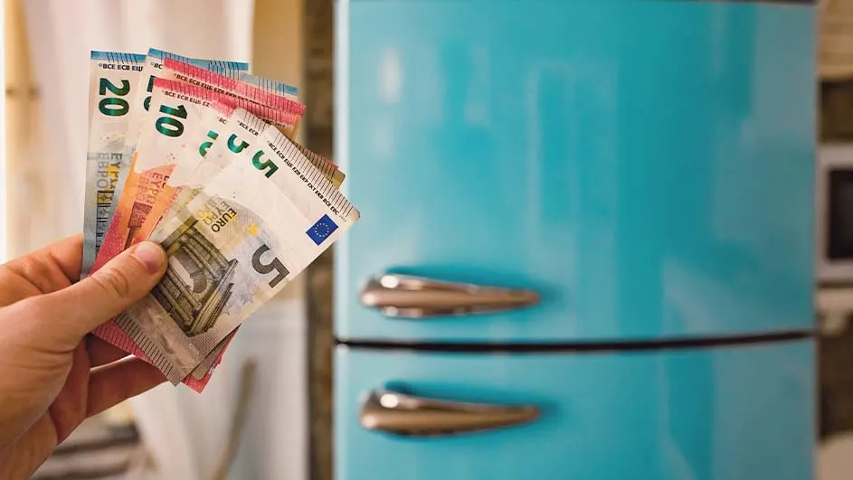 Une main tient des billets de 5, 10 et 20 euros devant un réfrigérateur bleu à deux portes avec des poignées argentées.