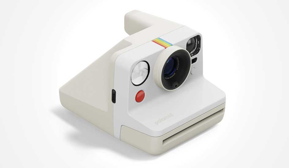 Appareil photo Polaroid blanc, ligne arc-en-ciel, grosse lentille, flash rond et bouton rouge. Design rétro et moderne.