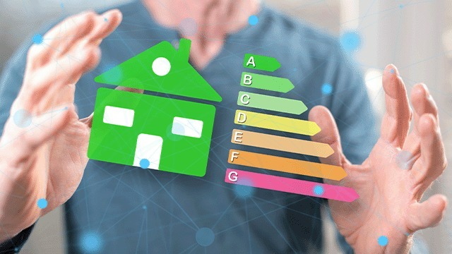 Een groene huisvorm en energie-efficiëntielabel (A-G) zweven tussen twee handen tegen een vage blauwe achtergrond.