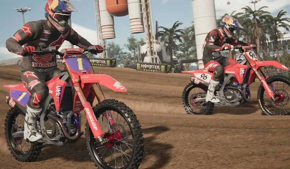 Deux motos rouges sur une piste de terre, avec des palmiers et des structures en arrière-plan.