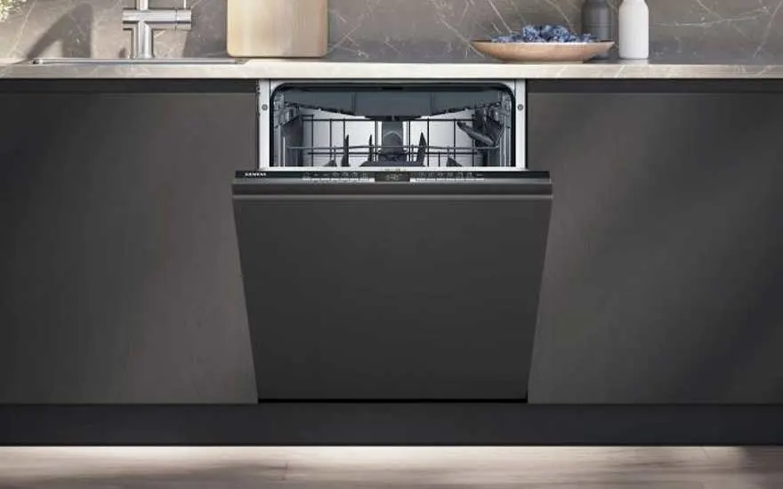 An open, dark-grey dishwasher is built into dark-grey kitchen cabinets under a light countertop.