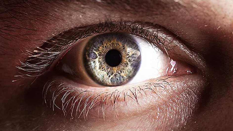 Nauw close-up van een menselijk oog met een iris in blauw, goud en bruin, omringd door wimpers.