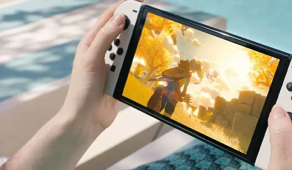 Une personne tient une Nintendo Switch près de la piscine, jouant à un jeu coloré avec un paysage ensoleillé à l’écran.