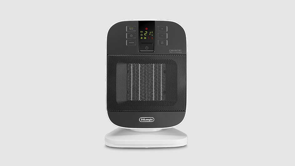 A black and white DeLonghi ceramic heater stands on a white base against a grey background.