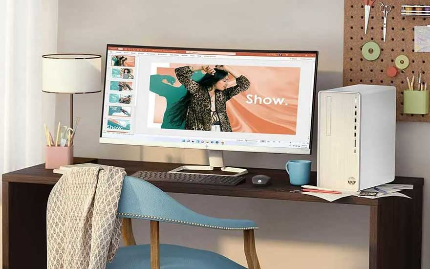 Un bureau avec grand écran incurvé affiche une présentation, près d’une tour PC blanche, lampe, tasse et mur créatif.