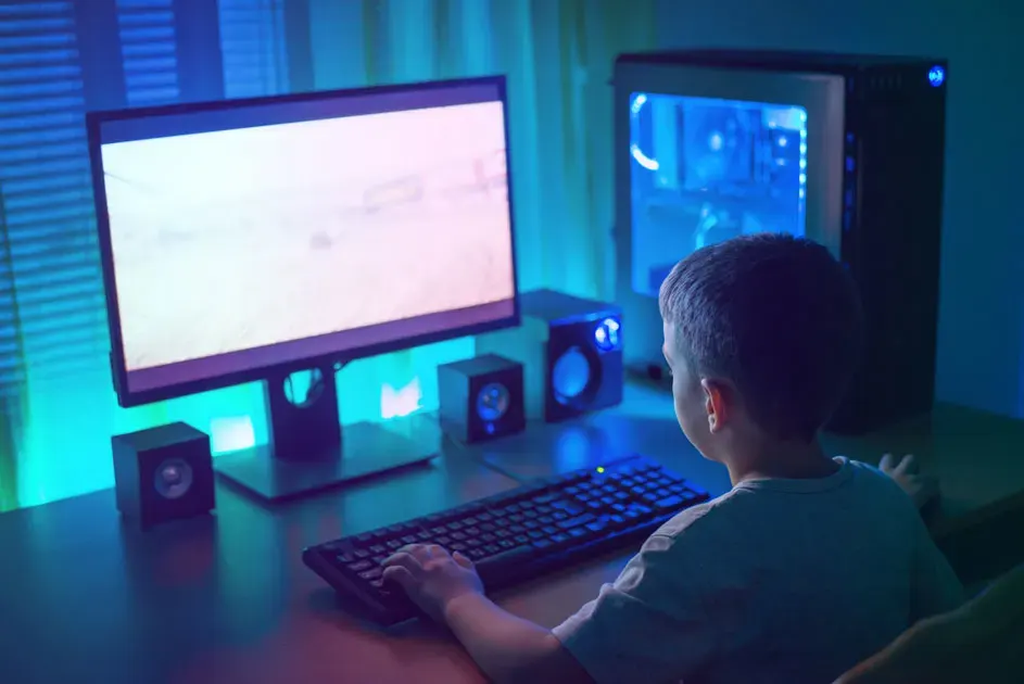 Un écran d'ordinateur, un clavier et des haut-parleurs sont sur une table. Une tour d'ordinateur est sur la droite.