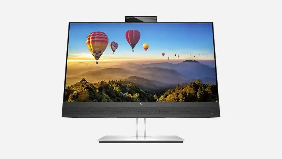 A modern all-in-one computer with silver stand displaying a colourful mountain landscape with hot air balloons on screen.