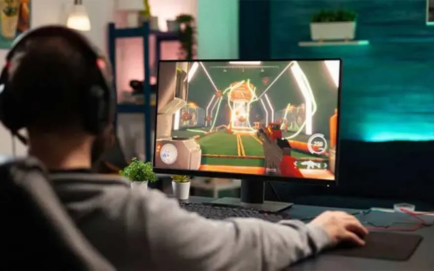 Bureau noir avec écran affichant un jeu vidéo. Le jeu a des couleurs vives et futuristes.