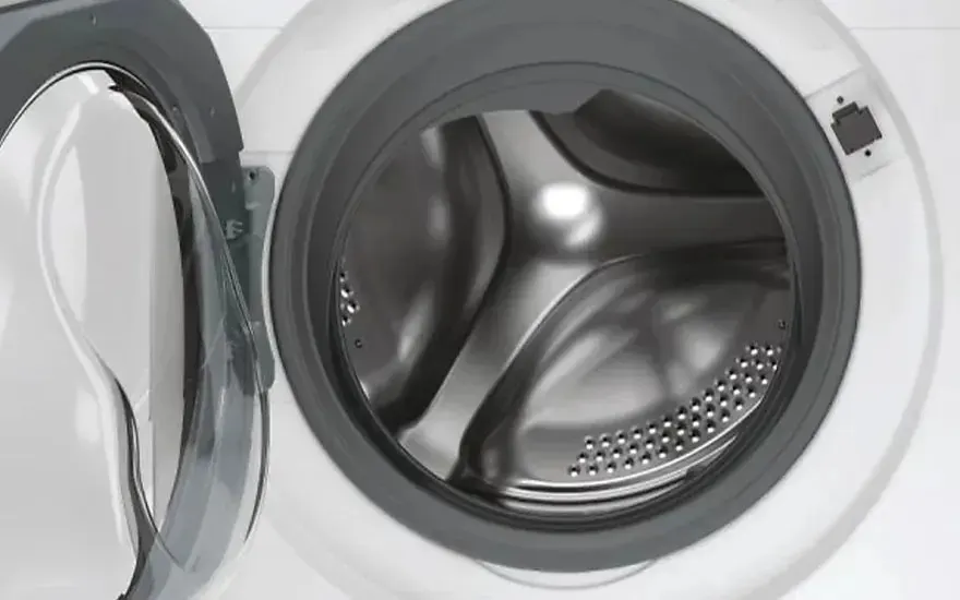 La porte ouverte d’un lave-linge vide révèle le tambour à l’intérieur, la marque n’est pas visible sur l’appareil.