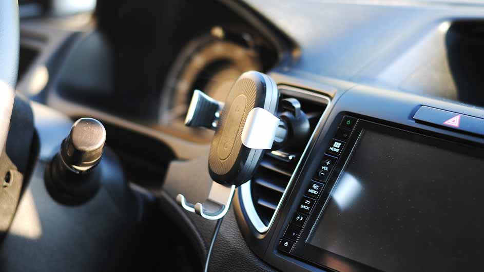 Support de téléphone noir et argenté fixé sur une grille d'aération de voiture, à côté d'un écran noir.