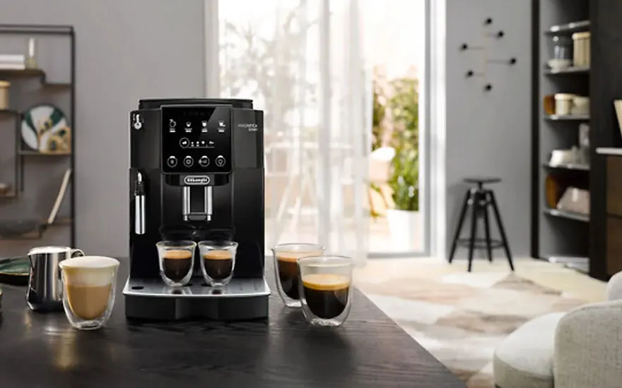 Zwarte koffiemachine met kopjes espresso op een donkere tafel. Achtergrond: raam, stoel en rekken.
