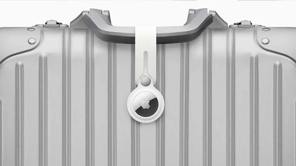 Een zilveren koffer heeft een witte Apple AirTag aan het handvat bevestigd.