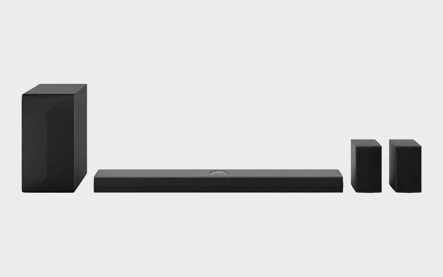 Een complete LG audioset met soundbar, subwoofer en twee achterspeakers staat symmetrisch opgesteld op een neutrale achtergrond.