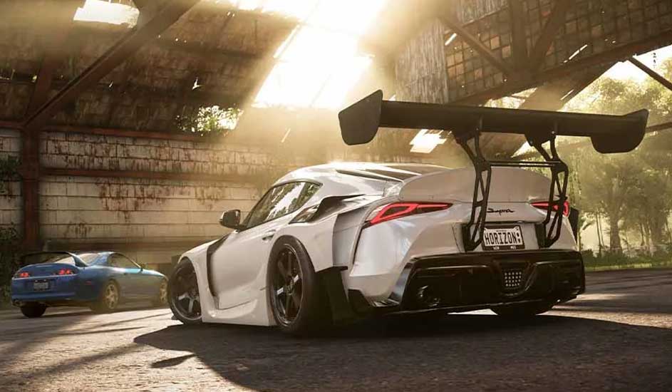 Une voiture blanche avec un aileron est garée dans un hangar. Une voiture bleue est visible en arrière-plan.