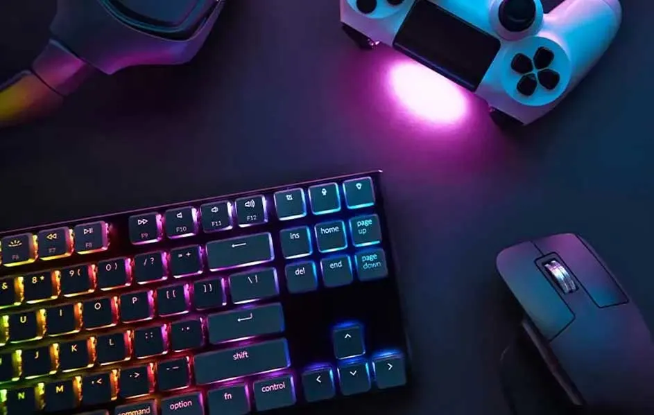 Een toetsenbord met RGB-verlichting, een witte controller, een muis en een headset op een donkere ondergrond.