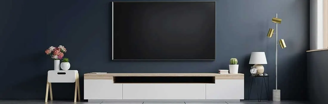 Living room with a large black TV on a blue wall, a white cabinet, and a lamp.