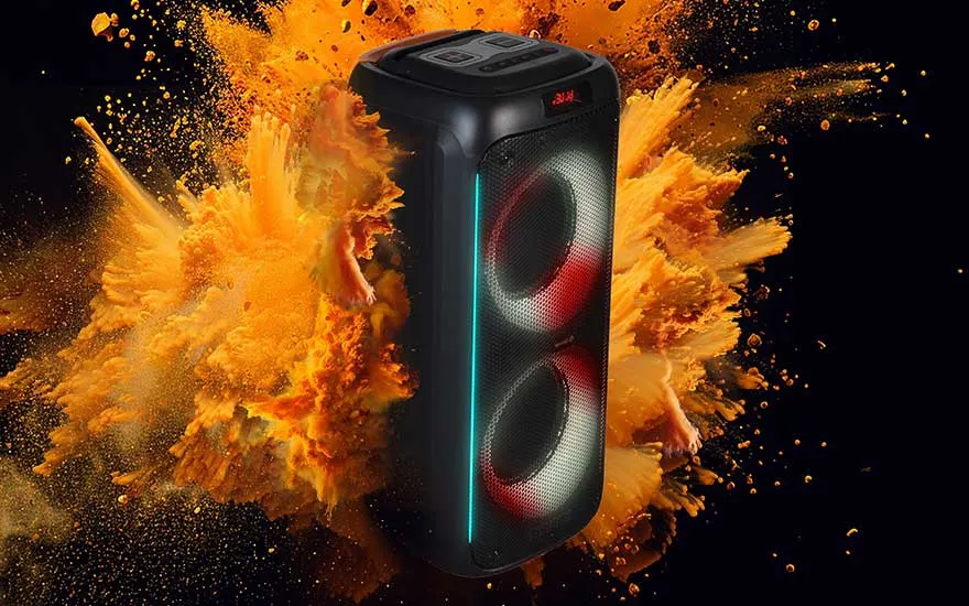 A black speaker with two lighted circles stands against a black background with an orange dust explosion.