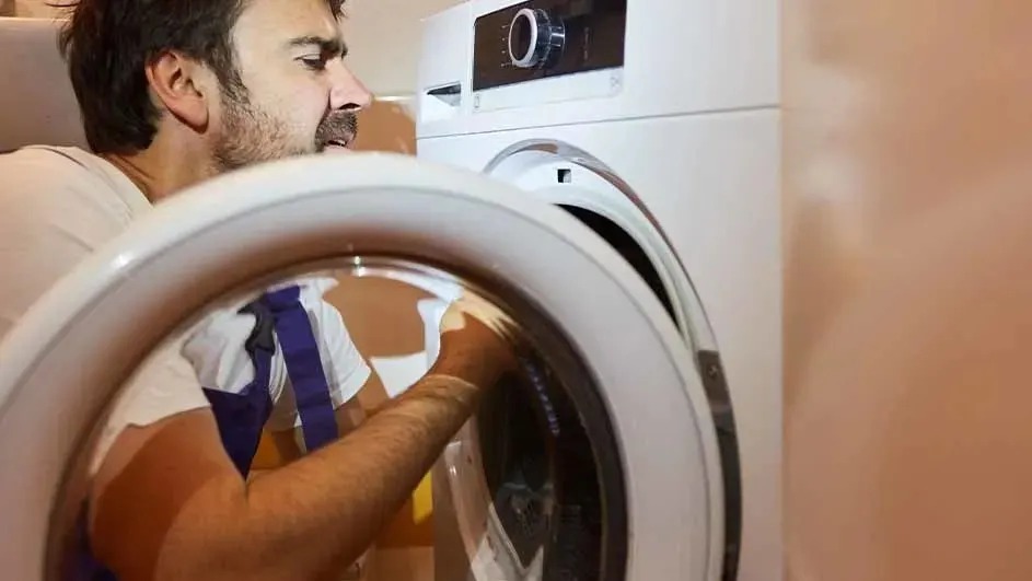 Une machine à laver blanche avec un hublot ouvert. Des vêtements sont visibles à l'intérieur.