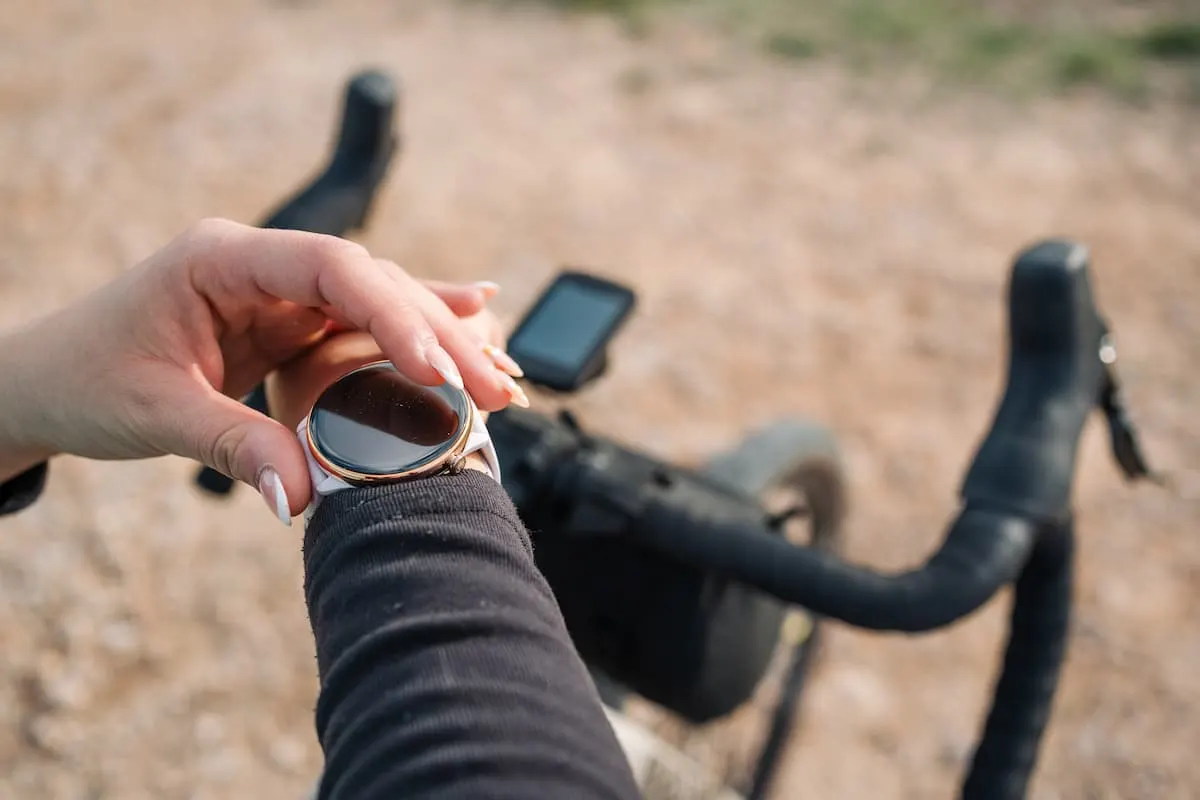 Persona tocando su smartwatch junto al manillar de una bicicleta.