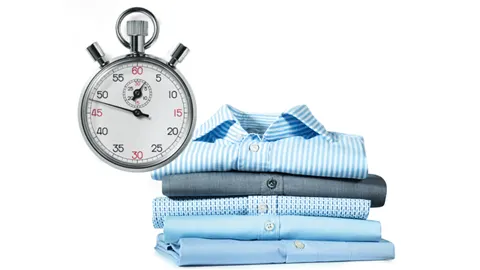 Un cronómetro junto a una ordenada pila de camisas en tonos azules perfectamente limpias y secas