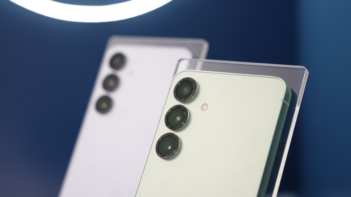 Dos teléfonos móviles con tres lentes de cámara cada uno, en soportes transparentes, sobre un fondo azul oscuro.