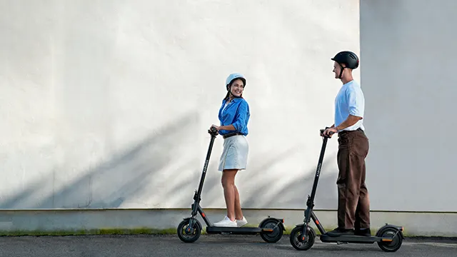 Dos personas circulando con el Xiaomi Electric Scooter Elite por la ciudad, mostrando su diseño moderno y compacto.