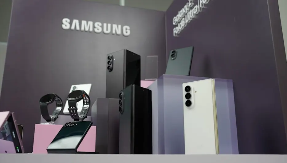 Expositor de Samsung con smartphones plegables, relojes inteligentes y teléfonos Galaxy sobre pedestales morados.