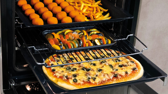 Horno con 3 bandejas extraídas a diferentes niveles mostrando diferentes preparaciones en cada una de ellas. 