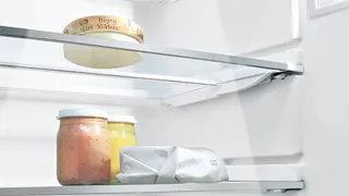 Detalle del refrigerador abierto, con la iluminación LED atravesando los estantes de cristal