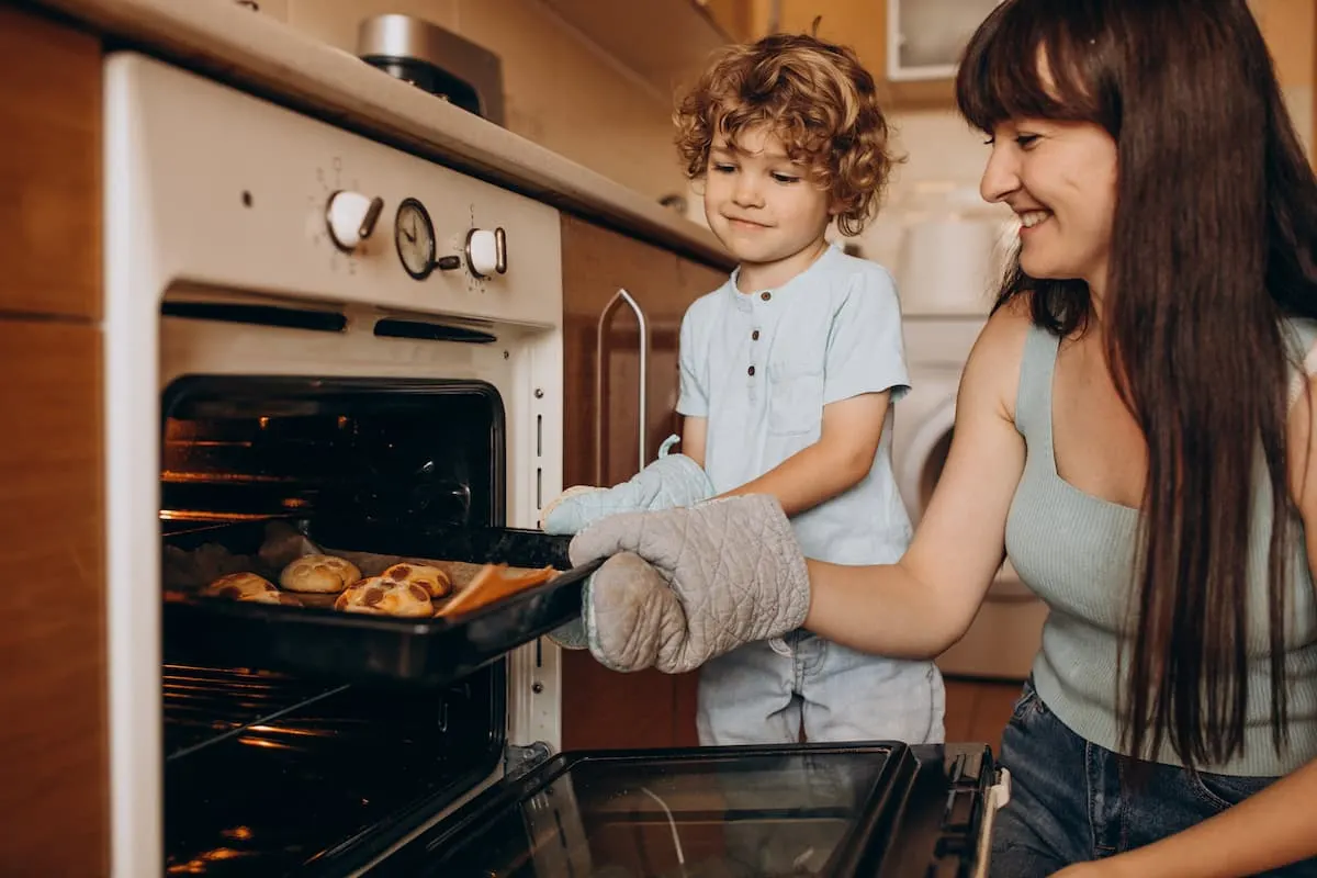 Madre e hijo sacando una bandeja con comida del horno.