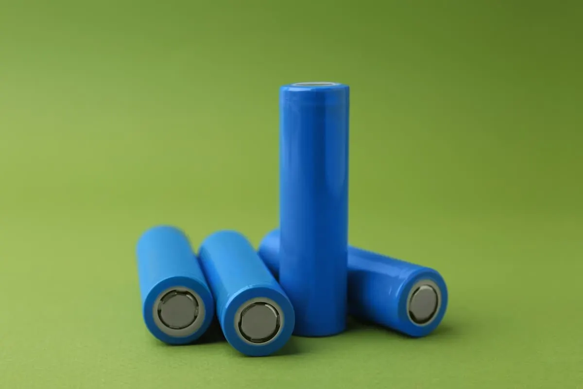 Cuatro baterías cilíndricas azules apiladas sobre fondo verde.