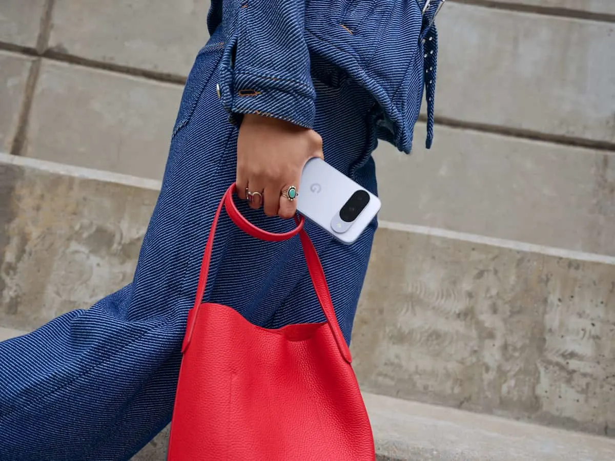 Persona caminando con un bolso rojo y un smartphone en la mano.