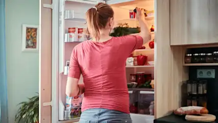 Mujer organizando los alimentos en el frigorífico de su cocina.